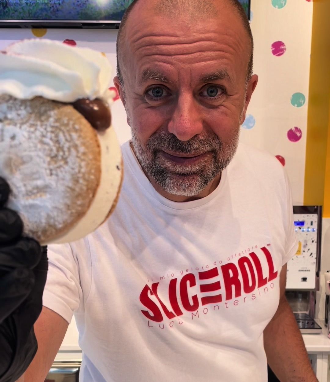 Luca Montersino porge un dolce Sliceroll indossando la maglietta del marchio
