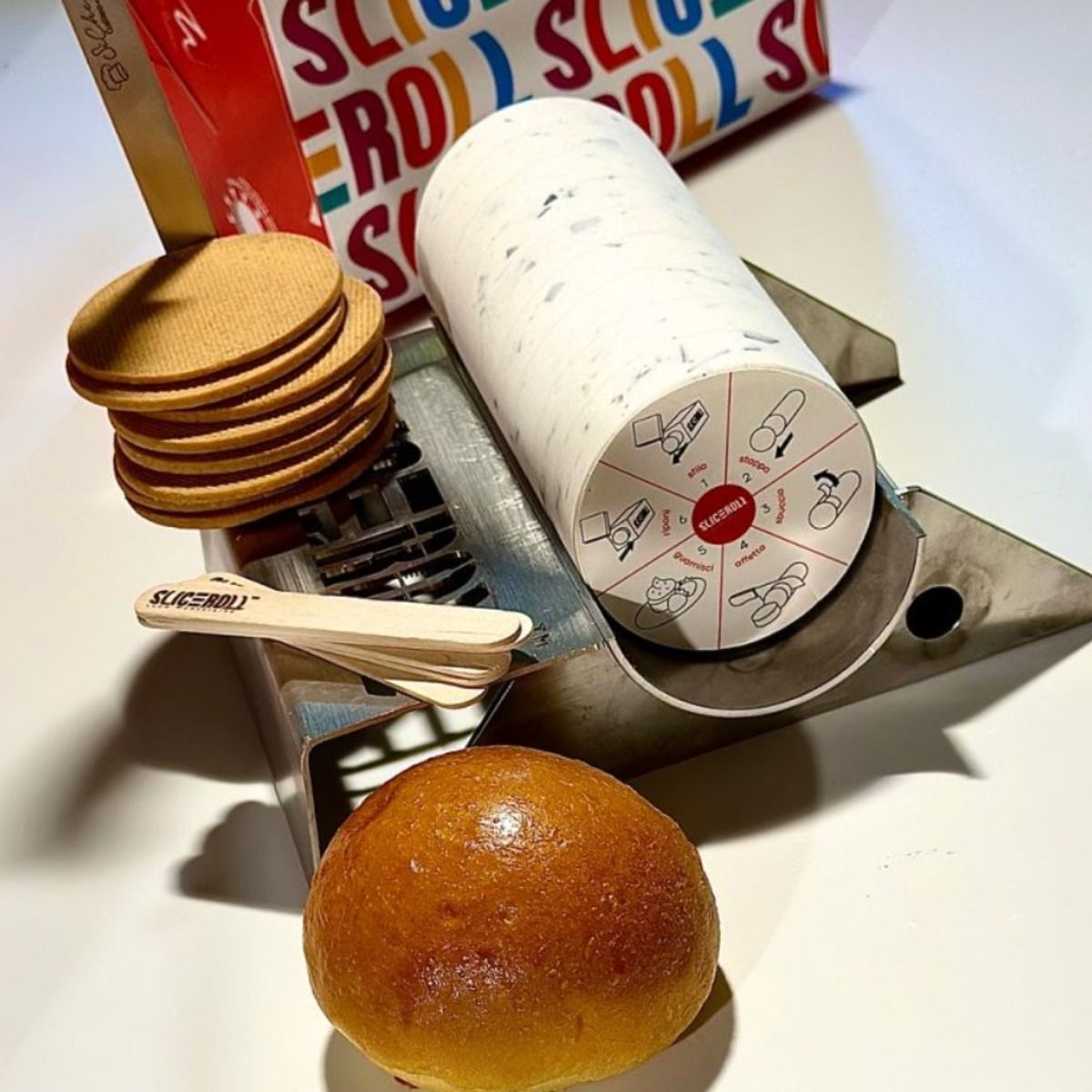 Taglierina, rotolo con etichetta, biscotti, brioche e stecchi su fondo bianco